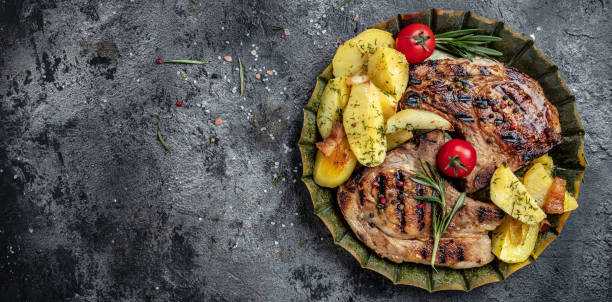 istock Grilled pork steak with potatoes and vegetables. Long banner format. top view 1399137950