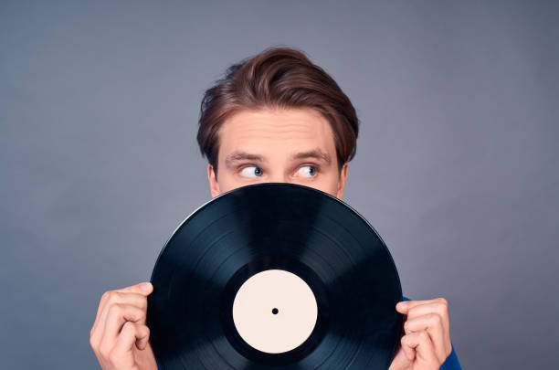 istock Handsome young man with blue eyes in a blue sweater and record player. 1399140460
