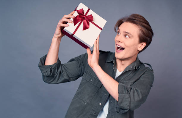 istock A happy excited young guy shakes a box with a gift. 1399140849