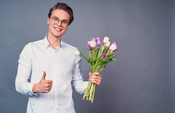 istock Handsome man holds pink and white tulips. 1399140923