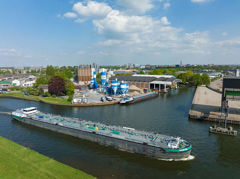 Large fuel barge ship sailing on the Zwolle-IJsselkanaal at the Voorst industrial area in Zwolle during a springtime day seen from above.