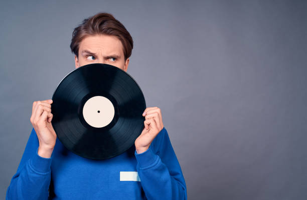 istock Handsome young man with blue eyes in a blue sweater and record player. 1399141532