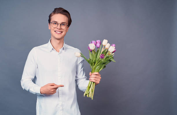istock Handsome man holds pink and white tulips. 1399141545