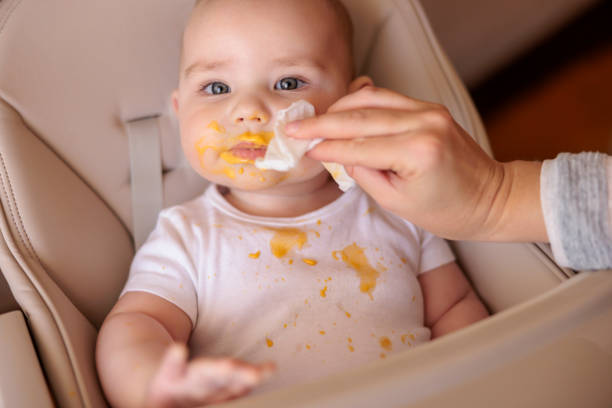 Mother wiping baby using wet wipes after meal stock photo