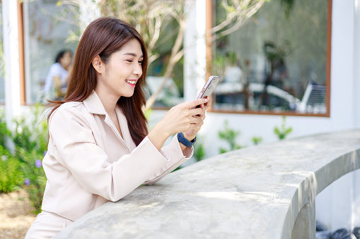 Asian businesswoman use smartphones during working in the coffee shop.
