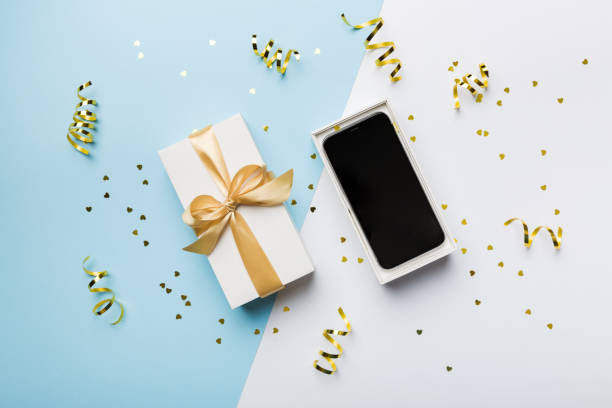 istock Opened gift box with gold ribbon and smartphone on color background, top view. Blank open box packaging mockup , Template for your design - branding mockup 1399143195