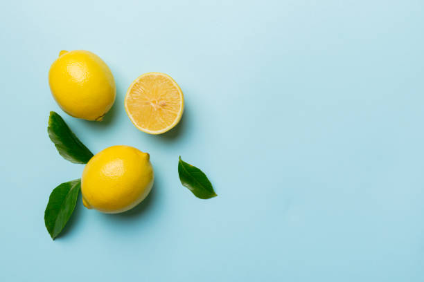 istock Many fresh ripe lemons with green leaves on colored background, top view, space for text 1399143198