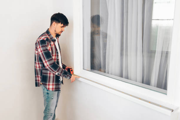 istock worker builder measures the window sill with a construction tape measure 1399144595