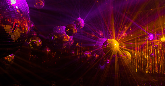 purple and yellow rays are reflected from mirrored disco balls