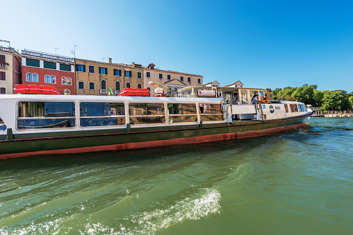 Venice, Italy - June 2, 2021: Actv (Municipal Company for Public Transport) Ferry Boat or Vaporetto with tourists in motion in the Venice Lagoon on a sunny spring day, Grand Canal (Canal Grande), on a sunny spring day. UNESCO world heritage site, Veneto, Italy, Europe.