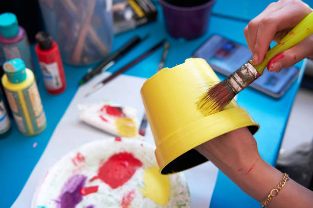 mujer de la mano sosteniendo un pincel o pincel y pintando una maceta o maceta de plástico decorativa. - flower pot fotografías e imágenes de stock