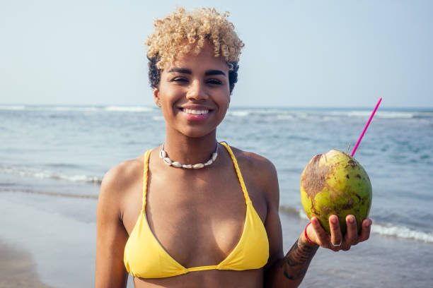 istock hispanic latin beautiful female drinking coco nut water seashells on the neck 1399150820