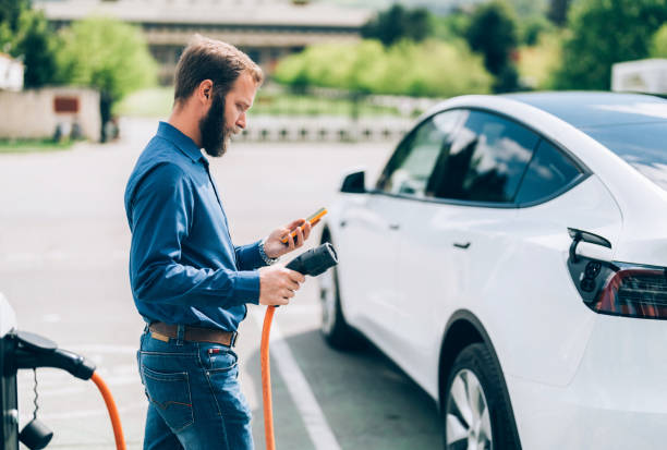 Man charging electric car stock photo
