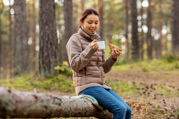 istock woman drinking tea and eating sandwich in forest 1399151924
