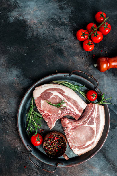 istock pork, beef, chop on a bone. fresh raw meat with spices and rosemary. vertical image. top view. place for text 1399151939