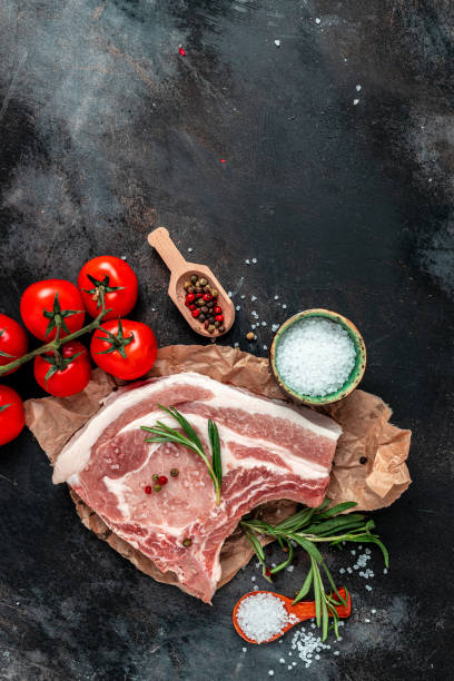 istock Fresh raw pork meat with ingredients ready for cooking on black table. vertical image. top view. place for text 1399151964