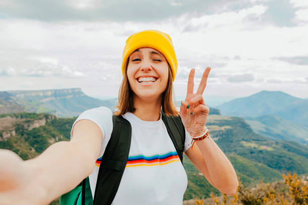 mochileiro jovem e alegre tirando selfie nas montanhas rochosas - tourist backpack smiling cheerful - fotografias e filmes do acervo