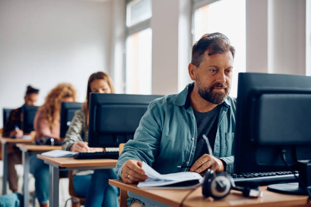 studente maturo che utilizza il pc desktop durante l'apprendimento in classe. - adulto foto e immagini stock