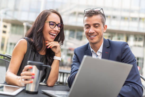 istock Office colleagues discuss and laugh over a laptop sitting with a coffee outdside. 1399155310