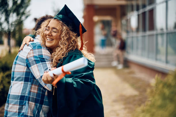 Happy graduate student embracing her father after graduation ceremony. Happy student hugging her father after receiving diploma on graduation day at the university. college student and parent stock pictures, royalty-free photos & images