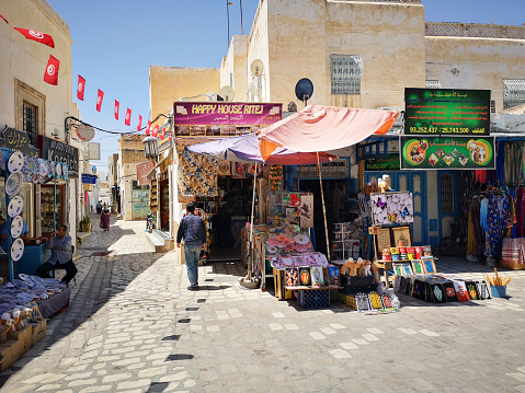 Kairouan, Tunisia: May 17, 2022: Tourists shop at the medina for souvenirs while locals buy essential products.