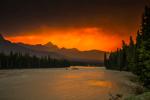 Dramatic sky with red clouds over Banff National Park, Alberta Canada. Bow River in the foreground. Silhouette of the Canadian Rockies in the background.