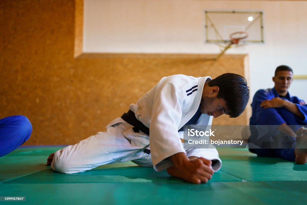 Martial artists stretching before training Two young male martial artists stretching and warming up before training, front view Stretching Stock Photo