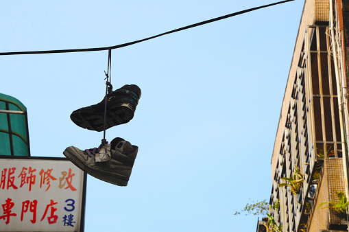 A pair of sneakers hangs high on a wire in the air\
