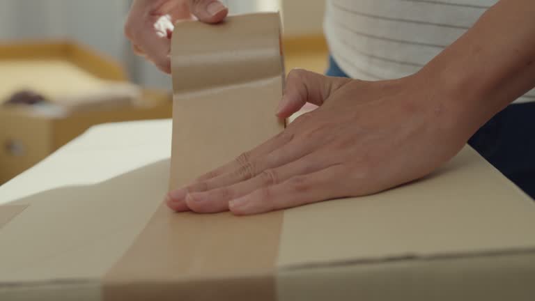 Close up of young Asian woman packing their belongings before moving to new house.