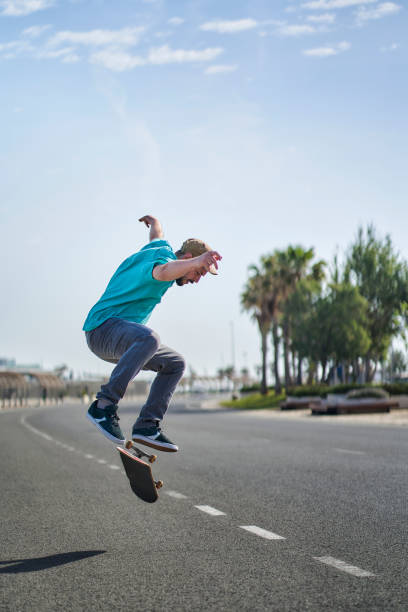 istock a man doing an ollie flip with his skateboard down a road 1399164823