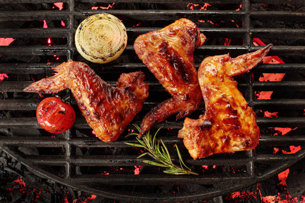 istock Grilled chicken wings on barbeque grill with vegetables and herbs, top view 1399164943