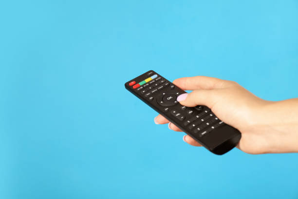 istock Woman holding remote control on light blue background, closeup. Space for text 1399168007