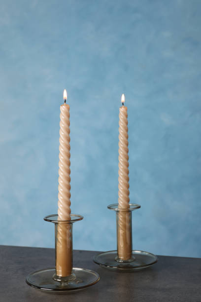 istock Holders with burning candles on black table near light blue wall 1399168158