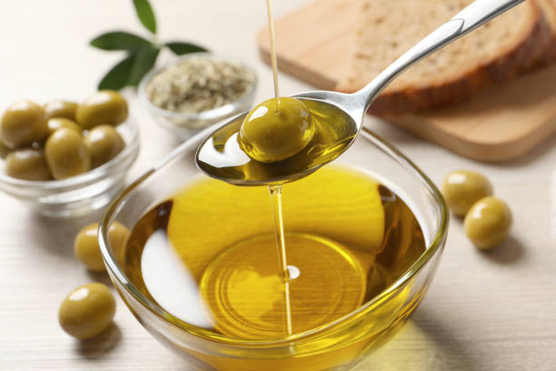 istock Pouring fresh olive oil into spoon above bowl on table, closeup 1399168905