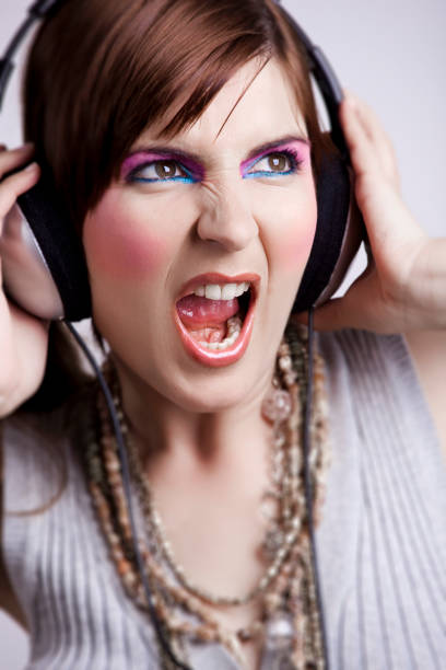 Portrait of black woman in green with headphones on in studio, listening to music. Young happy girl with makeup, beauty and wireless earphones streaming a song, podcast or radio for fun and to relax