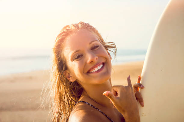 Pretty surfer girl at the beach with her surfbard