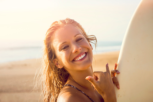 Pretty surfer girl at the beach with her surfbard