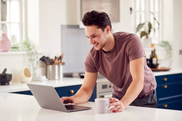 istock Transgender Man Working From Home Looking At Laptop On Kitchen Counter 1399169581