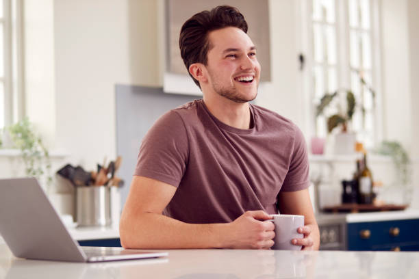 istock Transgender Man Working From Home Looking At Laptop On Kitchen Counter 1399169619
