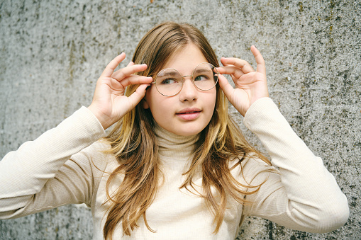 Outdoor portrait of young happy teenager girl wearing glasses
