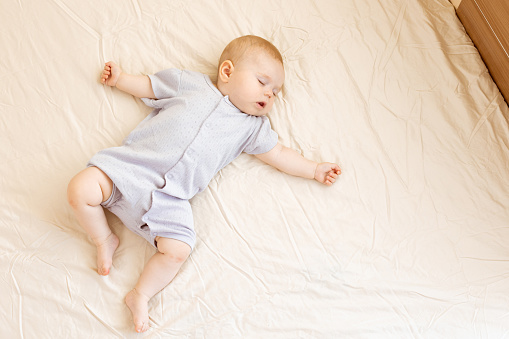 Peaceful baby lying on a bed and sleeping at home