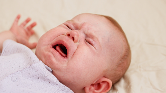 Little baby girl crying on her bed at home