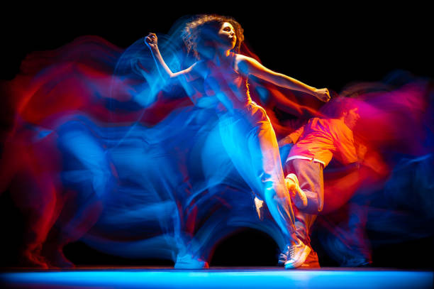 retrato dinâmico do homem e menina dançando hip-hop em roupas de estilo esportivo em fundo escuro no salão de dança em luz neon mista. cultura juvenil, breakdance, movimento - sports or fitness fotos - fotografias e filmes do acervo