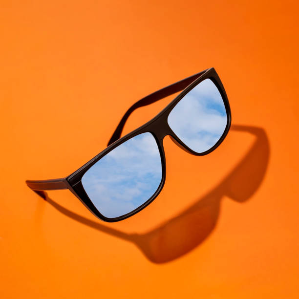 istock black sunglasses with a reflection of the blue sky with clouds on a pink background. 1399172514