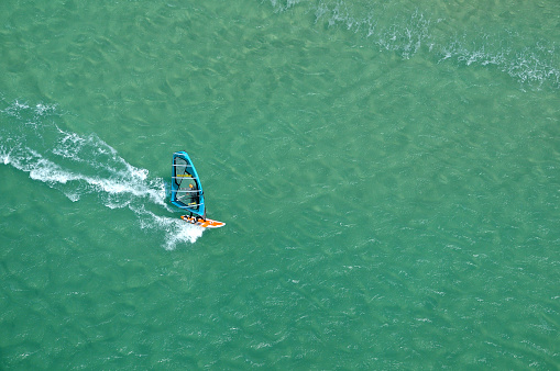 A drone captures wind surfers catching waves along the coastal line of Fuerteventura, big blue open waters with high winds.