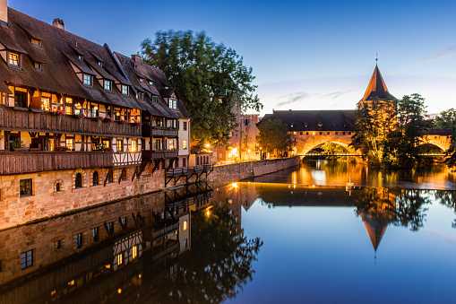 A colourful and picturesque view of the half-timbered old houses on the banks of the Pegnitz river in Nuremberg, Franconia, Germany, illuminated at night