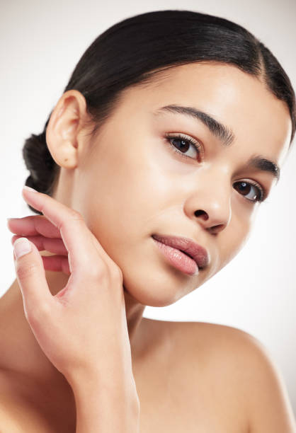 istock Young beautiful mixed race woman touching and feeling her face posing against a grey studio background. Confident hispanic female posing against a background 1399174077