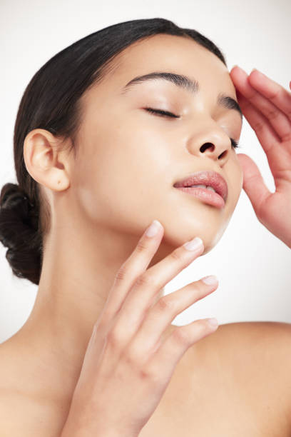 istock Young beautiful mixed race woman touching and feeling her face while posing against a grey studio background. Confident hispanic female posing against a background 1399174872