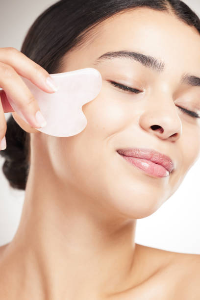 istock Beautiful young happy woman doing her skincare routine standing against a grey studio background alone. One content female using a gel pad on her face while standing against a background 1399175216