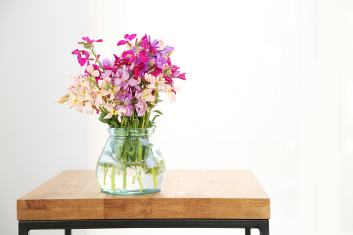 A beautiful springtime arrangement of flowers in a hobnail glass jar. The bouquet contains roses, peonies, and sweet peas. Shot against a bright white background. There is a path which may be used to delete the reflection if desired. Extremely high quality faux flowers.